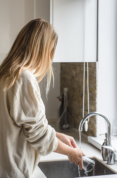 Woman hands washing dish or pouring glass with running fresh drink water at kitchen faucet