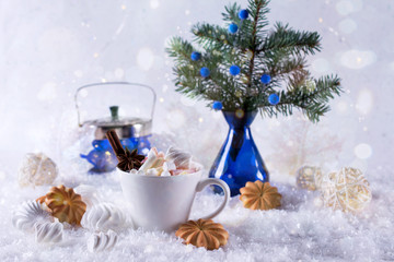 A cup of hot cocoa with marshmallow or coffee with cinnamon and sweet cookies on the snow background