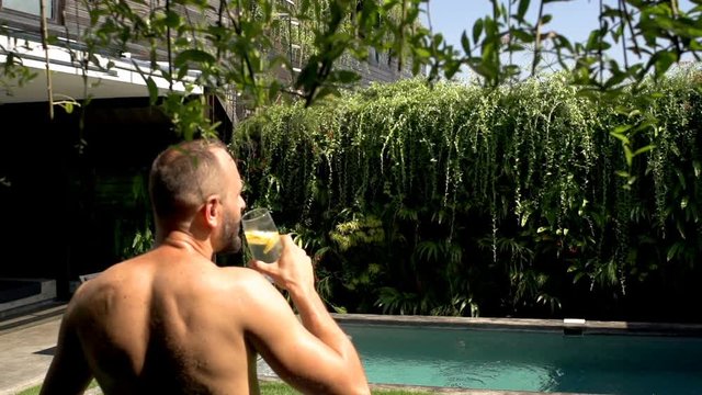 Man going outside to the garden while drinking water, steadycam shot, slow motion shot at 240fps
