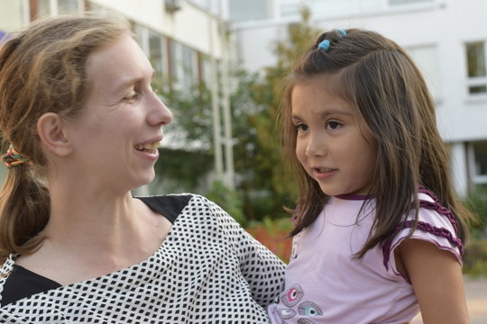 кавказская мама с латинской дочерью на руках весело проводят время  