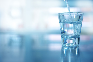 single glass shot with movement water for drinking in blue background