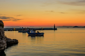 Fototapeta na wymiar A beautiful sunrise at the sea. Pier with fishing boats in Kokkari village, Samos island, Greece