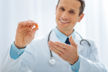 It is for you. Positive delighted doctor keeping smile on his face and looking forward while...