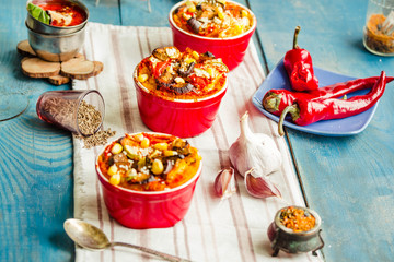 Portioned casserole.from corn grits and vegetables in tomato sauce in red ceramic baking molds. Vegan holiday christmas dinner.Healthy lifestyle and plant-based food concept.
