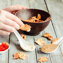 Close up of a female hands eating a delicious Mexican snack. Healthy chips a tortilla, nachos with organic classic sauce.