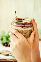 Fototapeta na wymiar Superfoods concept: overnight chia pudding with fresh berries and whipped coconut cream in a hand. Selective focus. Place for text.