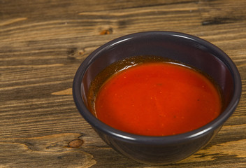 Red hot chilli sauce in ceramic bowl on a wooden background. with copy space