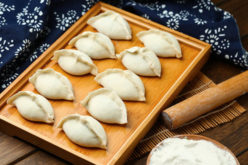 Fototapeta na wymiar raw dumplings on wooden plate with flour and rolling pin