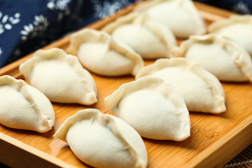raw dumplings on wooden plate with flour and rolling pin