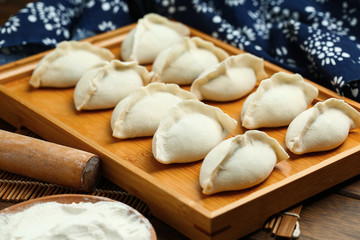 Fototapeta na wymiar raw dumplings on wooden plate with flour and rolling pin