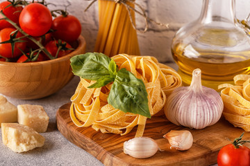 Products for cooking - pasta, tomatoes, garlic, olive oil, basil.