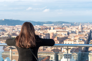 Woman tourist is looking on city Rome from a high point.