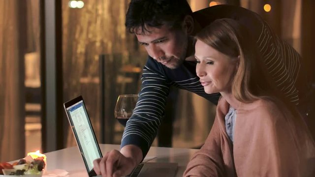 Handsome man and young woman talking and looking on screen noteebook