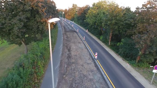 Kamerafahrt über Baustelle des Teilabschnitts einer Bundesstraße mit Bäumen mit Sichtwinkel in Höhe der Straßenlaternen