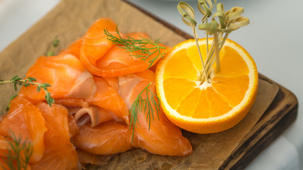 still life of salmon and cut in half orange on wood plate