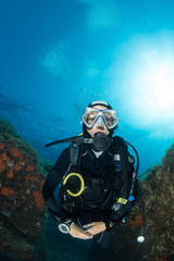 woman scuba diving over rocks in the Mediterranean Sea