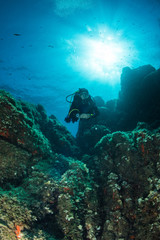woman scuba diving over rocks in the Mediterranean Sea