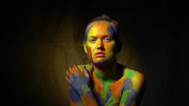 An embarrassed woman with light gray eyes and body art on her body, slow motion