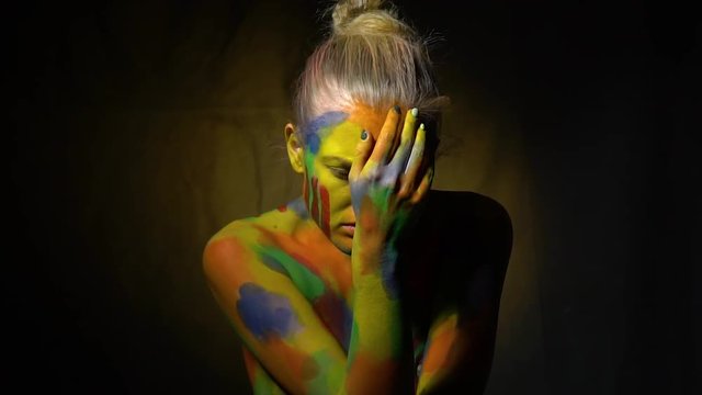 Blonde woman in body art covers her head with her hand and slowly raises her head, slow motion