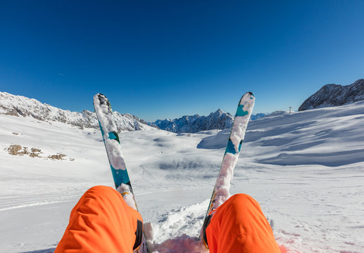 Skier sitting in powder snow, watching Alpine scenery