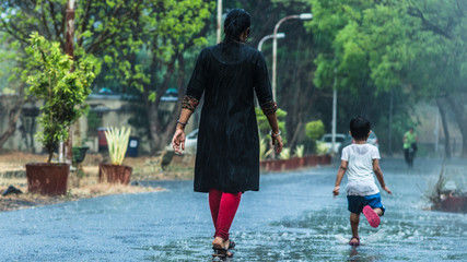 Mother and daughter welcoming the first monsoon showers by playing in heavy rain