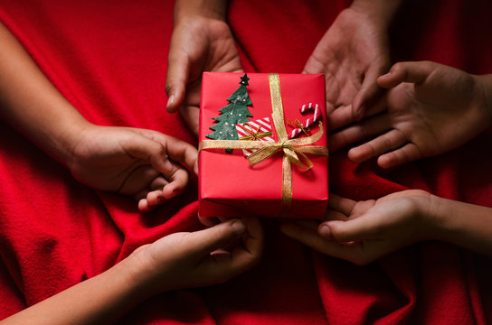 Group of Hand Kids Hold Christmas Gift Box on Red Background.