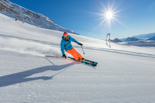 Skier on piste running downhill in Alpine landscape.