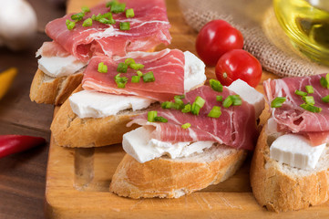 Italian prosciutto and cheese bruschetta. Antipasti on grilled baguette bread.