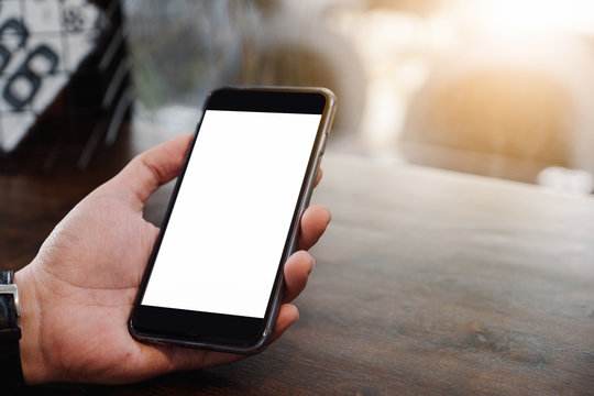 Mockup image of man's hands holding white mobile phone with blank screen in modern cafe