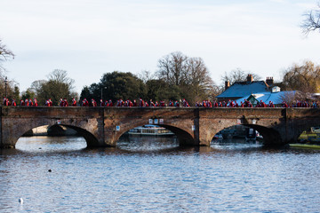 Group of santa claus running across bridge