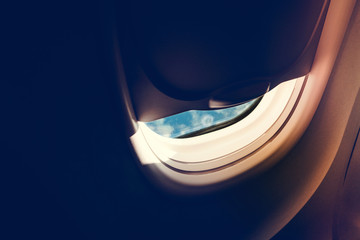 Airplane windows seat ajar with blue sky in the morning. Passenger open airplane window seat for look out to the blue sky with copy space for text.
