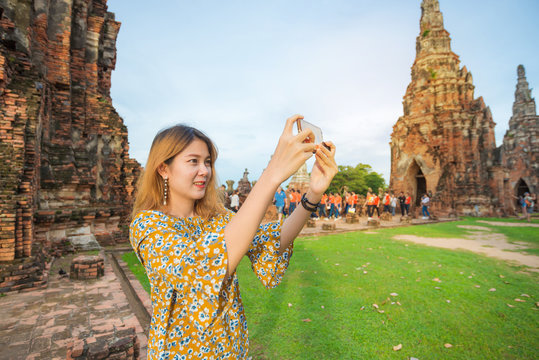 Close up of young asian girl taking smartphone photo with mobile phone at Wat Chaiwatthanaram temple in Ayutthaya.