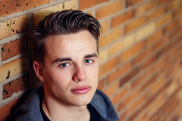 Close up of handsome young man against brick wall