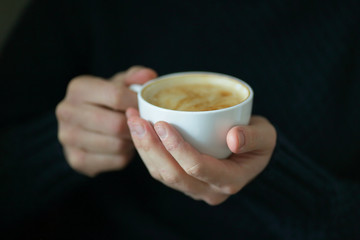 White cup with coffee in man's hands