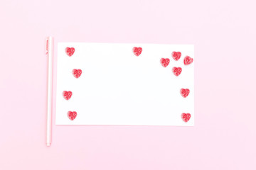 White sheet of paper with a pen and candies in the form of a heart. Valentine's Day