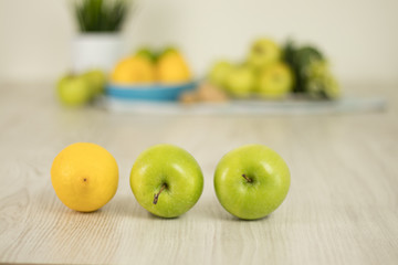 Lemon and green apples with blurry background on white wooden table. Detox juice preparation ingredients.