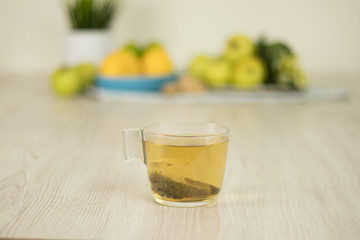 Tea cup with fruits blurry background on white wooden table. Tea preparation ingredients.
