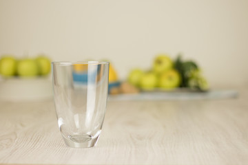 Empty glass with fruits blurry background on white wooden table. Detox juice preparation ingredients.