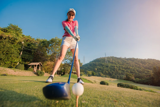 woman golf player holding wood driver to hit a golf ball in Addressing the ball, ready to hit away from tees off to fairway ahead