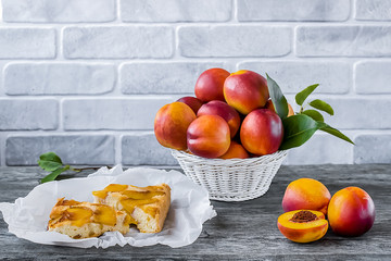A pie with nectarines on a gray wooden table.