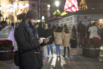 Man in christmas night image sending sms by smarphone app