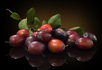 Ripe fresh plum and branch of plum on a black background