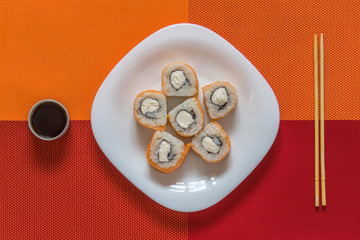 White plate with Philadelphia rolls, bamboo sticks and soy sauce on the coloured napkin. Serving. Japanese style minimalism.