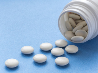 Round white pills spilled from a white bottle. Dope. Vitamins