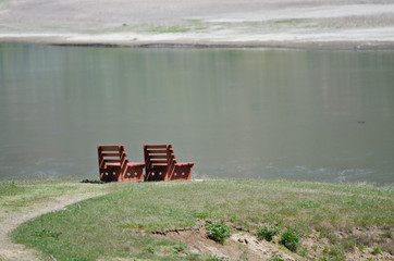 Lonely Pair of Wooden Benches Waiting Patiently Beside the Water