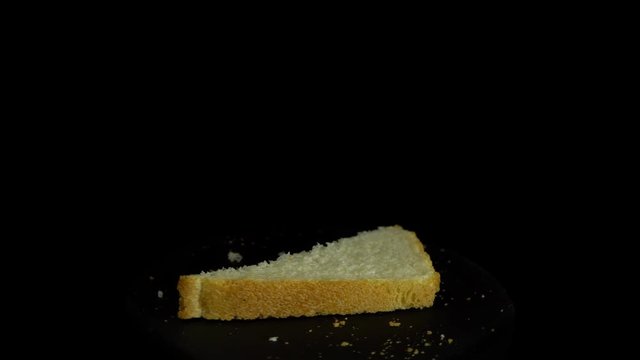 Close-up of sliced white wheat bread rotates against a black background, loopy motion.