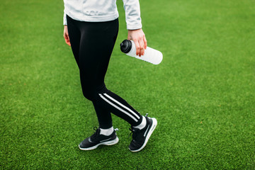 Girl after training, running or sports a rest. In the foreground, a bottle of water. The Girl works in the open, fresh air.