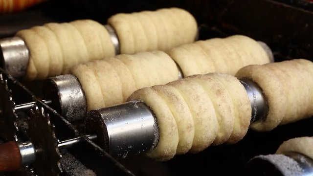 Close up sweet Trdelnik baking on grill and rolling, this spit cake is popular in Europe, Austria, Hungary, Slovakia and Czech, especially in Prague