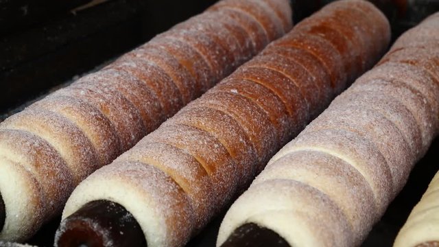 Close up sweet Trdelnik baking on grill and rolling, this spit cake is popular in Europe, Austria, Hungary, Slovakia and Czech, especially in Prague