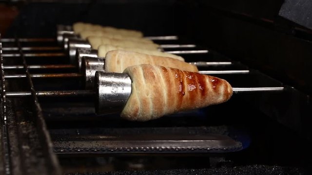 Close up sweet Trdelnik baking on grill and rolling, this spit cake is popular in Europe, Austria, Hungary, Slovakia and Czech, especially in Prague